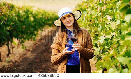 Attractive Winemaker Woman Holding A Glass Of Red Wine In Her Hand And Looking At The Camera. Female