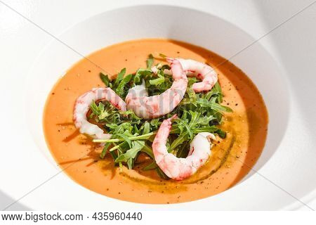 Summer Spanish soup gazpacho with shrimp and rocket salad isolated on white background. Healthy cold tomato soup with prawns. Clean eating for diet.Healthy food in restaurant menu. Seafood gazpacho