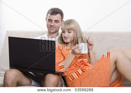 The guy sitting with his laptop on the couch, sitting next to a girl with a Cup of tea
