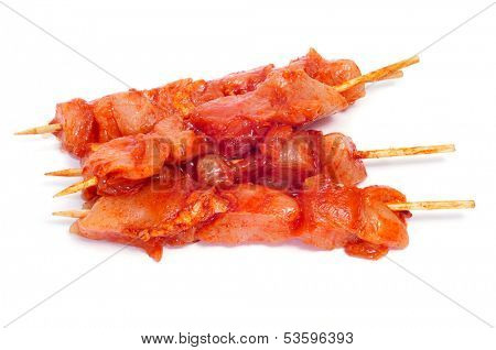 closeup of some raw spiced chicken meat skewers, on a white background