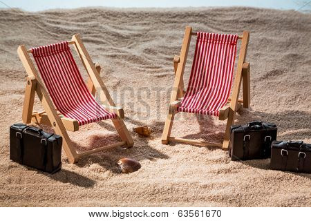 kkleine deck chairs on the sandy beach with suitcase
