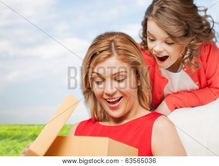family, child, holiday and party concpt - smiling mother and daughter with gift box