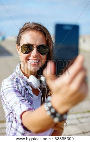 holidays and tourism concept - smiling teenage girl taking picture with smartphone camera aoutdoors
