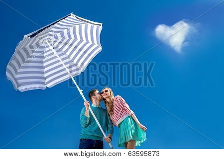Beautiful And Young Couple Kissing With Beach Umbrella On Blue Sky Background And Heart Shape Cloud