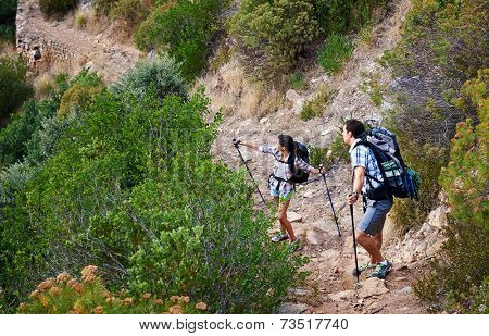 A couple walking along a hiking trail along a mountain range