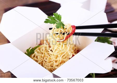 Chinese noodles in takeaway boxes on bamboo mat background