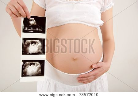 Close up on pregnant belly with baby's ultrasound.