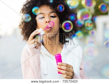 Afro woman blowing soap bubbles 