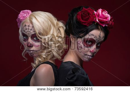 Portrait of two young girls in black dresses with Calaveras make