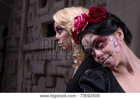 Portrait of two young girls in black dresses with Calaveras make