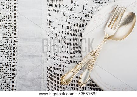 Closeup of vintage lacy white cloth handmade German silver fork and spoon