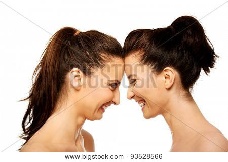 Two attractive sisters standing face to face.