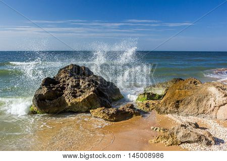 seashore with rocks and splashing waves with spray