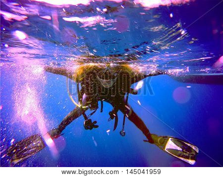 A scuba diver floating on the surface without the regulator. View of the scuba diver gear fins mask bcd and bubbles underwater in the deep blue sea of Limassol Cyprus.