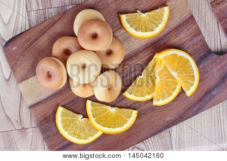 Milk donut with sliced orange home made on wood.