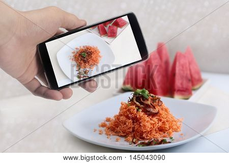 Using mobile phone to take photo a dish of mixed crispy rice noodle for share to social network. Selective focus.