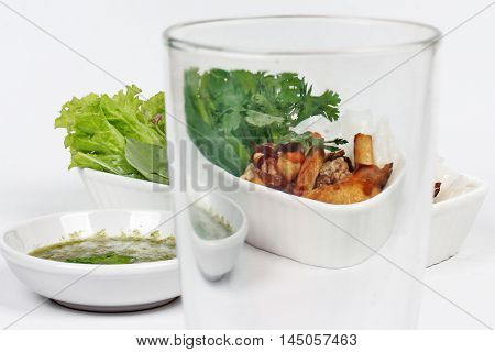 View roll noddle served with fried tofu and mixed vegetables through glass.Selective focus