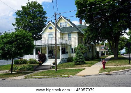 PETOSKEY, MICHIGAN / UNITED STATES - AUGUST 5, 2016: A yellow Victorian mansion, with a wraparound porch and a balcony, on Lake Street near downtown Petoskey.
