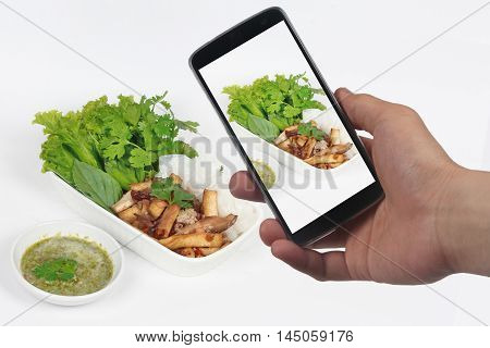 Friend using smart-phone to take photo roll noddle served with fried tofu and mixed vegetables for share to social network.
