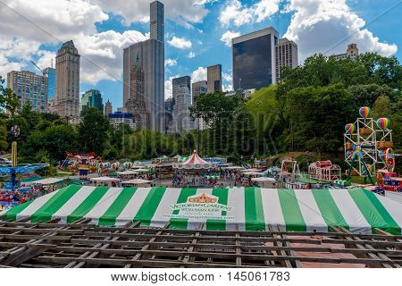 Central Park New York US -- August 31 2016. Victorian Gardens amusement park in Central Park with city skyscrapers in the backgound under a dramatic blue sky and white clounds. Editorial Use Only.