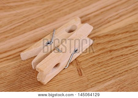 Pair wooden cloth pegs on wooden background.