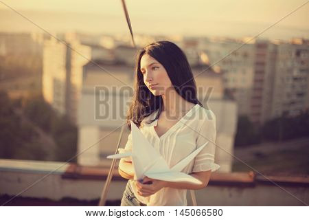 Beautiful young girl at the roof with origami paper crane in hands. Vintage tinted selective focus.