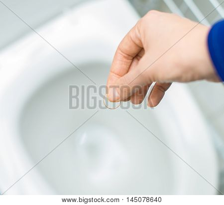 Divorce Concept. Woman Throwing Her Wedding Ring In The Toilet.