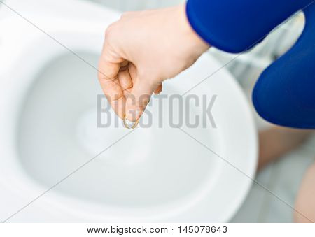 Divorce Concept. Woman Throwing Her Wedding Ring In The Toilet.