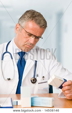 Absorbe dalgın olgun doktor bazı Tıp arıyorsunuz kutuları modern klinik ofisinde * lütfen no