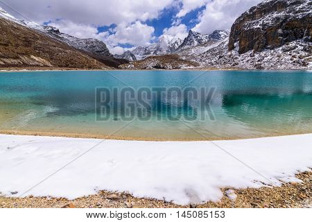 Green milk Lake is surrounded by snow on the mountains in Yading Nature Reserve, China.