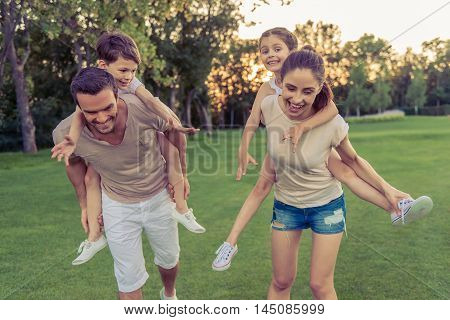 Beautiful happy family is smiling while having fun outdoors kids are sitting pickaback