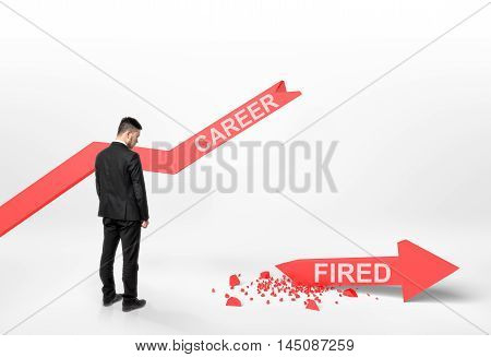 Back view of a businessman looking at broken arrow with 'fired' word that fall off the graph with 'career' word. Financial problems and troubles. Losing a job. Dismissing and discharging.
