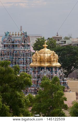 Madurai India - October 19 2013: The golden dome of the Meenakshi shrine on the temple grounds sits on top of short Vimanam. Other Vimanam in photo too.