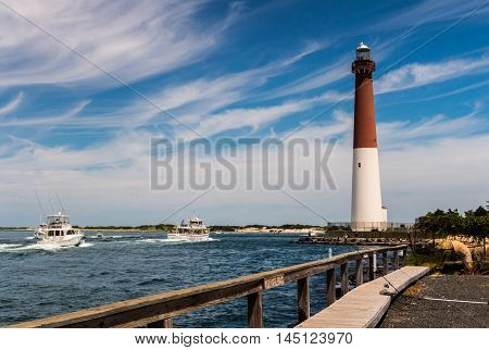 Fishing boats heading out to sea through Barnegat Inlet with Barnegat Lighthouse in background