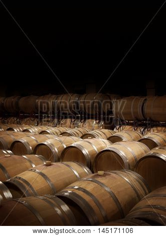 Wine cellar in warm ambiance. Wooden wine barrels at a winery. Balck copy space on top