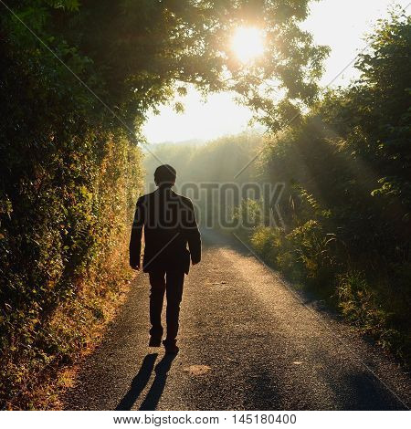 Alone man walking along a small country road in a misty morning