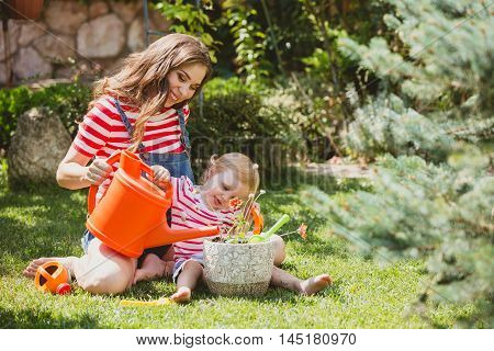 Pregnant woman with little daughter in the summer orchard cearing flower.