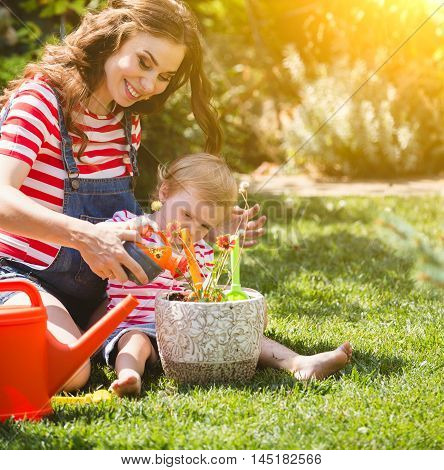Pregnant woman with little daughter in the summer orchard cearing flower.