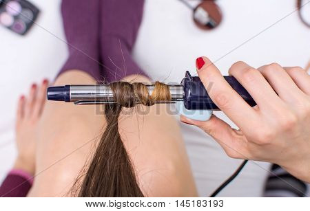 Woman Using Curling Iron On Her Hair
