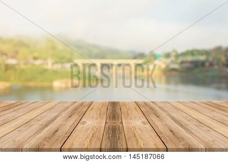 Wooden board empty table in front of blurred background. Perspective brown wood over blur wooden bridge - can be used mock up for display or montage your products. spring season. vintage filtered.
