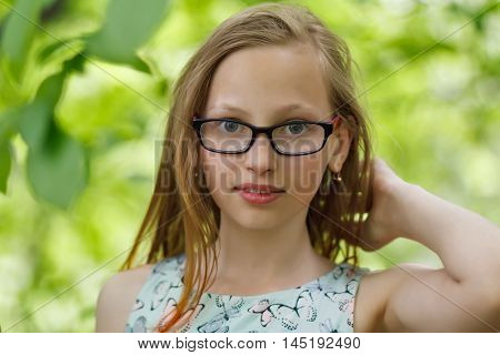 Twelve years old girl in glasses at green forest
