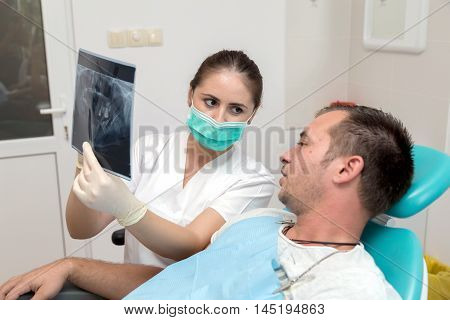Image of young patient and dentist showing him x-ray radiography, in the Dental Clinc