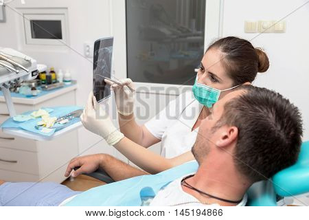 Image of young patient and dentist showing him x-ray radiography, in the Dental Clinc