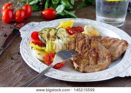 Grilled Steak Meat Pork And Grilled Vegetables On Brown Stone Background.