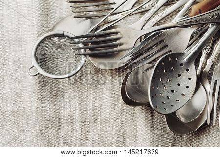 Vintage cutlery on rustic background. Old kitchen tools, retro colors.