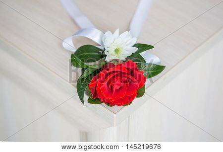 Red boutonniere and wedding bouquet lie on the wooden table