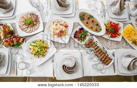 Beautifully decorated catering banquet table with different food snacks and appetizers with sandwich, caviar, fresh fruits on corporate party event or wedding celebration