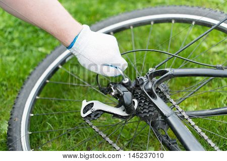 Man adjusts the derailleur bike. black moutain bike