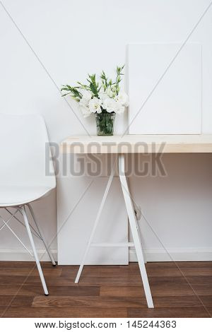 White scandinavian interior decor closeup: empty walls, designer chair, table and natural flowers.