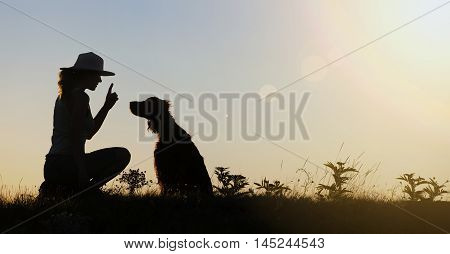 Silhouette of a female as training her dog - website banner